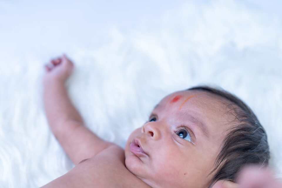 Close portrait of a newborn looking upward, lying on white fur