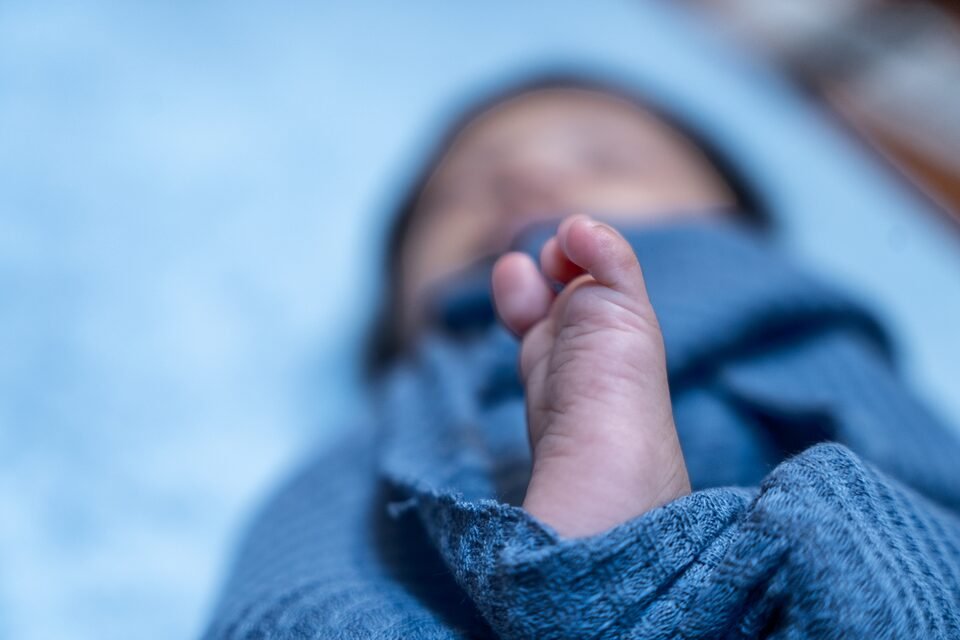 Macro photograph of a newborn’s toes against a soft blue knitted blanket