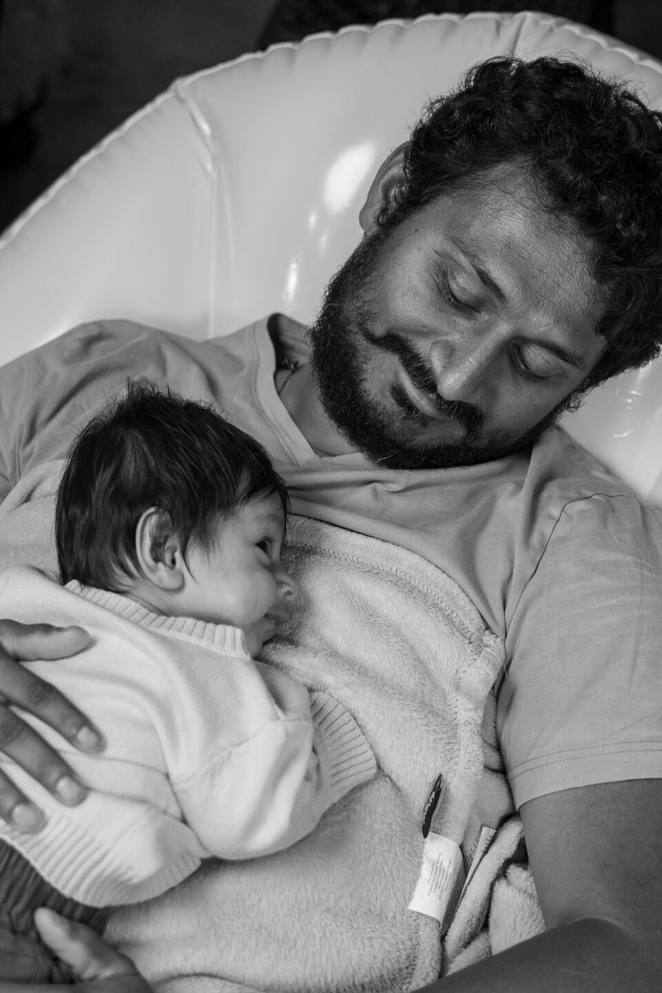 Black and white photograph of a father asleep with his newborn resting on his chest