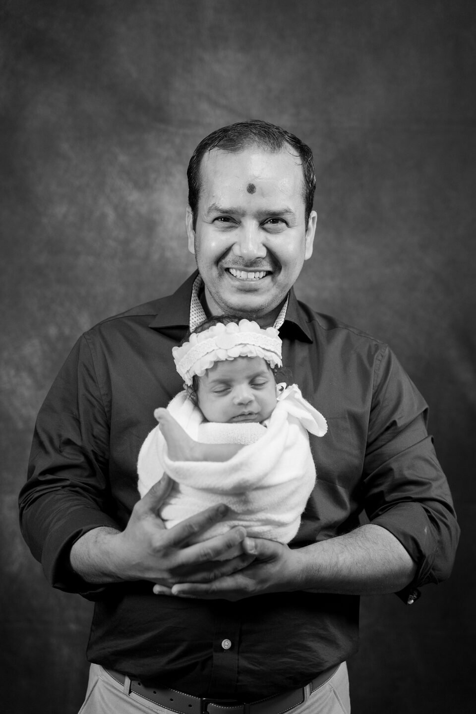 Black and white portrait of a father holding his newborn daughter close to his chest