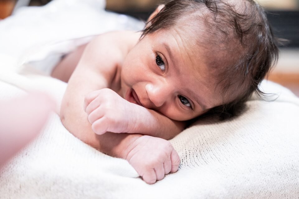 Baby resting her chin on her folded hands, looking directly into the camera