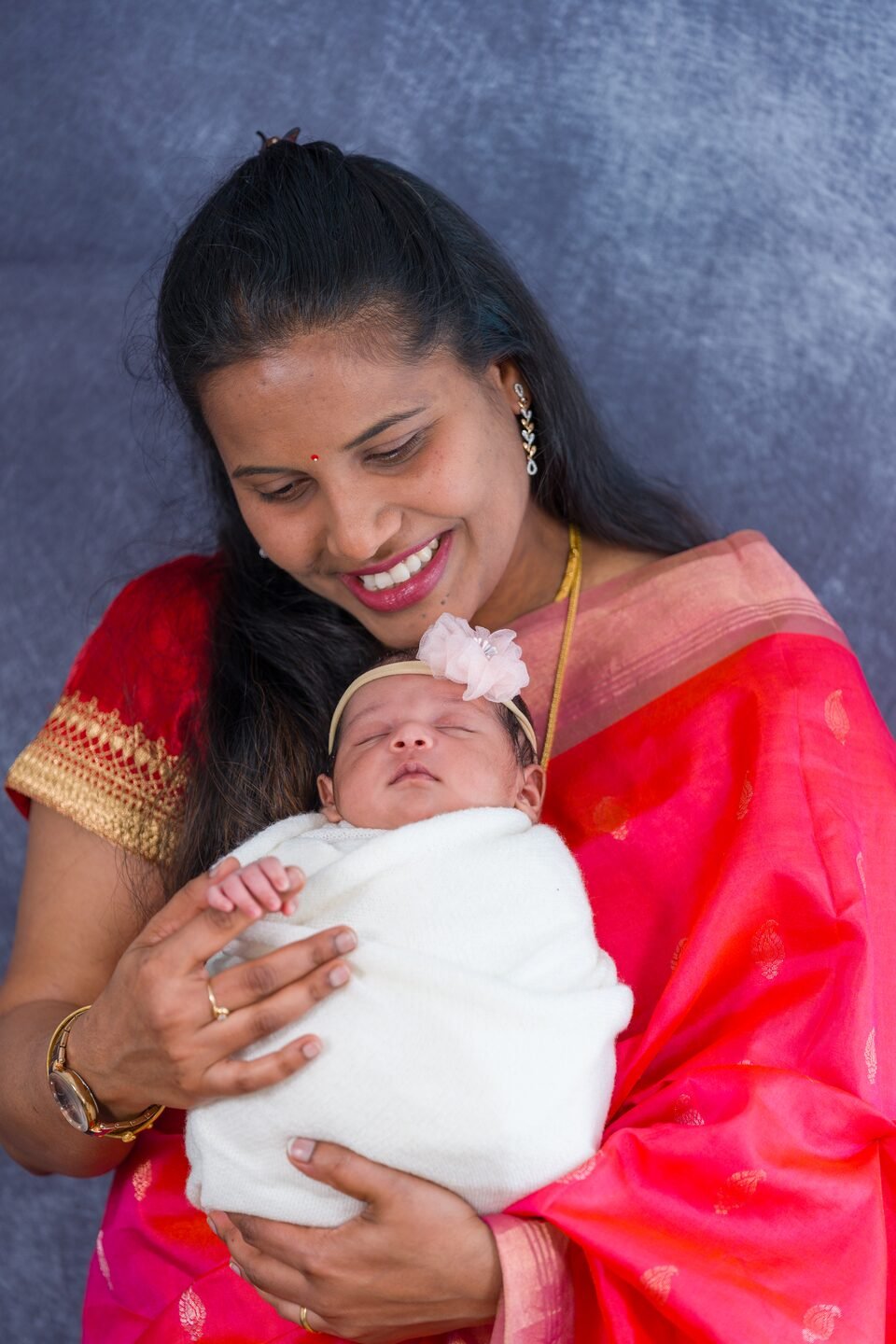 Mother smiling down at her newborn, cradled in a white wrap