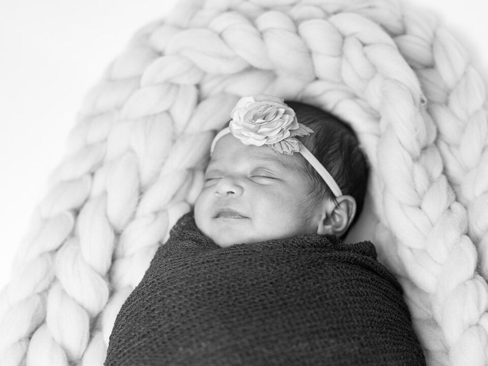 Black and white portrait of a newborn asleep on a chunky knit blanket